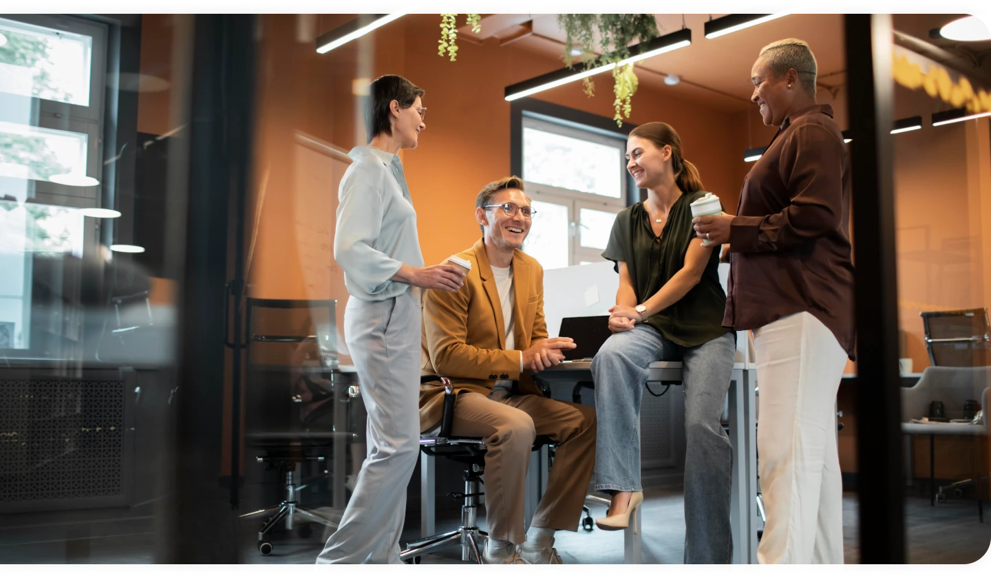 Four colleagues talking and smiling in an office